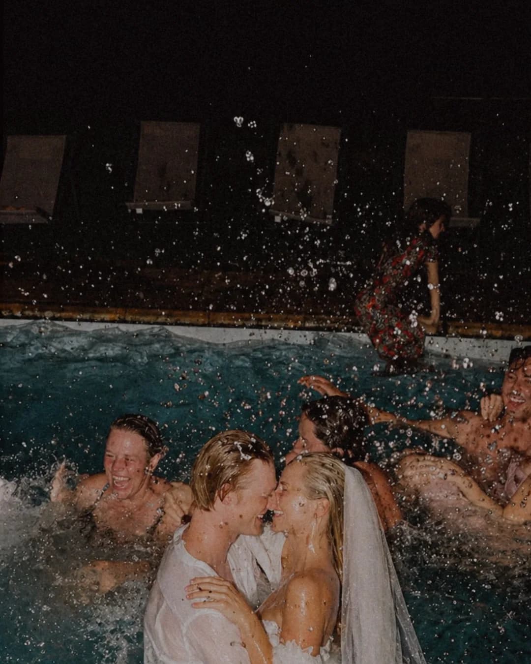A couple embracing in the pool among friends